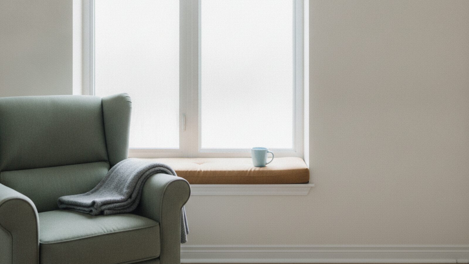 A quiet window seat in soft daylight with an empty chair beside it, suggesting absence without depicting a person